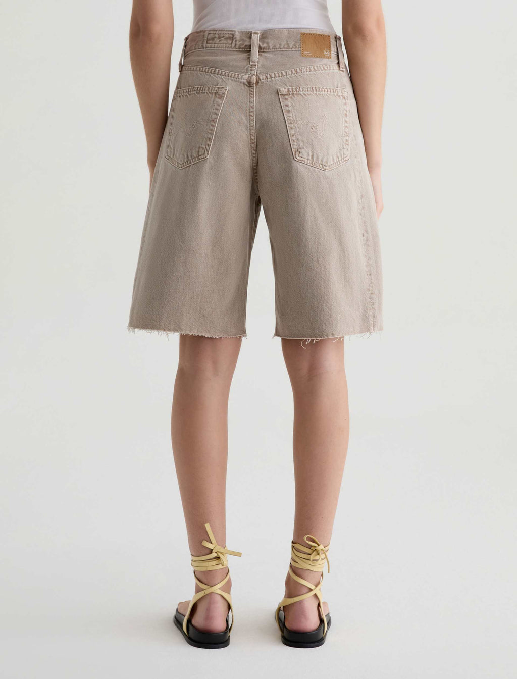 Person wearing beige shorts on a white background
