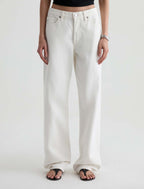 A person wearing off-white wide-leg jeans with a black crop top and black flip-flop sandals, shown from the waist down against a plain light background.