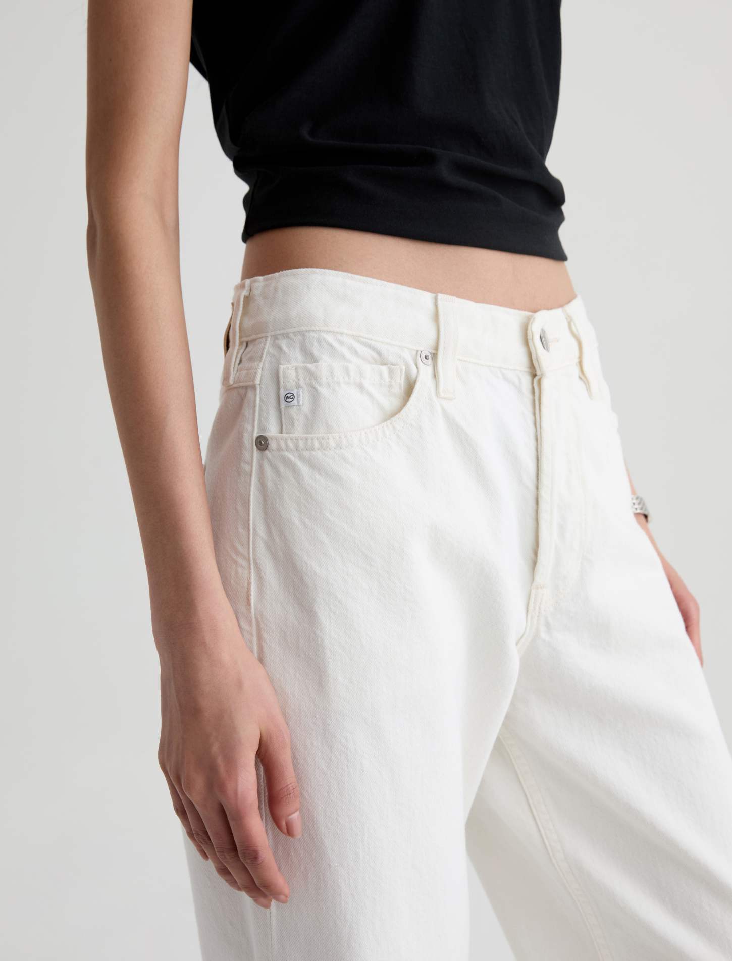 Person wearing white pants and a black top on a plain background