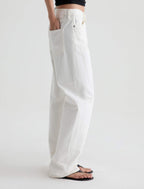 White wide-leg denim jeans shown on a model from the waist down, paired with black flip-flops against a clean white studio background.