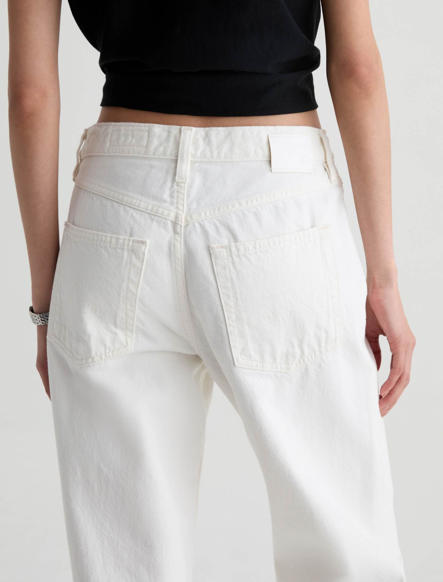 White high-waisted wide-leg jeans shown from the back on a model, paired with a black cropped top against a light gray background.