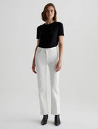 A woman standing straight facing forward, wearing a black t-shirt and mid-rise straight white jeans with visible five pockets, paired with black ankle boots.