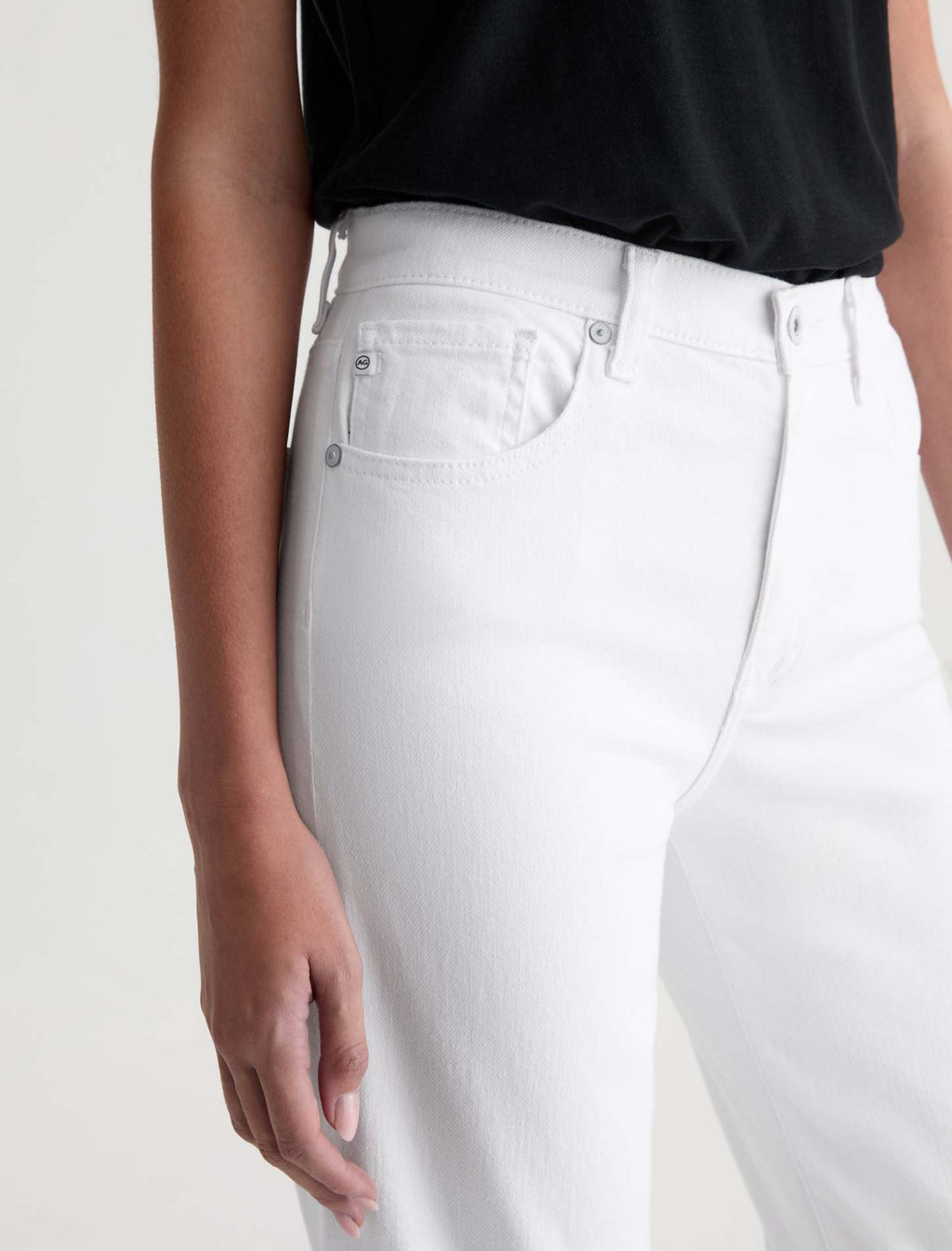 Person wearing white jeans and a black top on a plain background