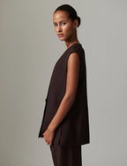 Woman wearing a brown sleeveless top and pants against a plain background