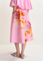 Pink striped dress with colorful floral patterns worn by a person on a white background.