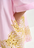 Pink fabric with gold embroidery on a light pink background