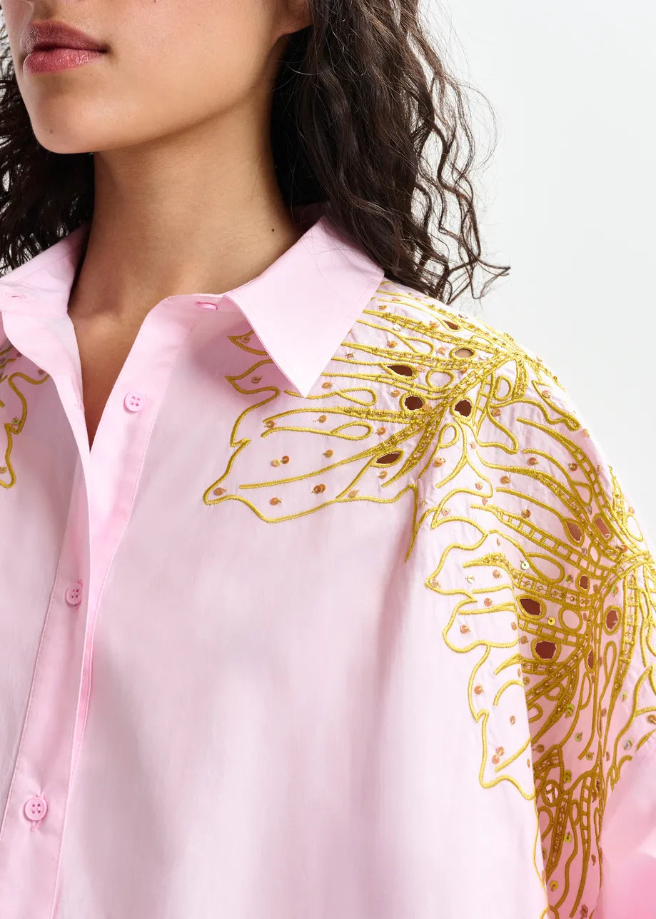 Close-up of a pink shirt with gold embroidery on a white background