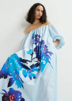 A woman modeling an off-the-shoulder striped and floral foil print dress with 3/4 length sleeves.
