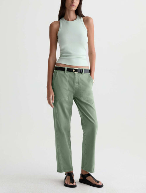 A model wearing sage green wide-leg cropped pants with a black belt, paired with a light mint green ribbed tank top and black sandals, against a plain white studio background.