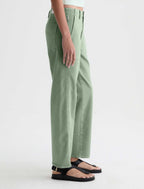 A person shown from the waist down wearing sage green wide-leg pants and black flat sandals against a clean light gray studio background.