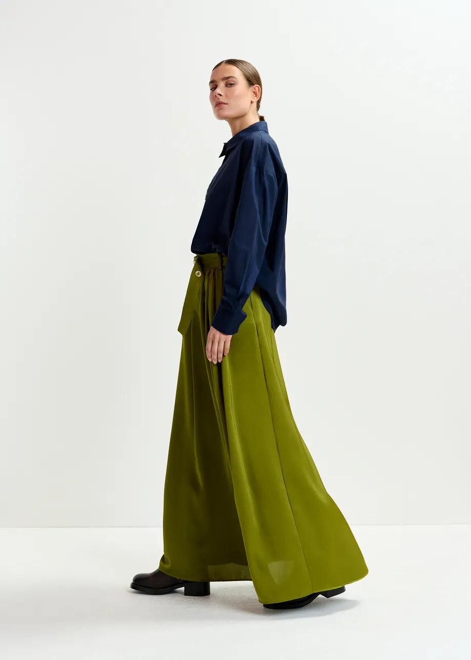 Woman wearing a navy shirt and green skirt on a white background