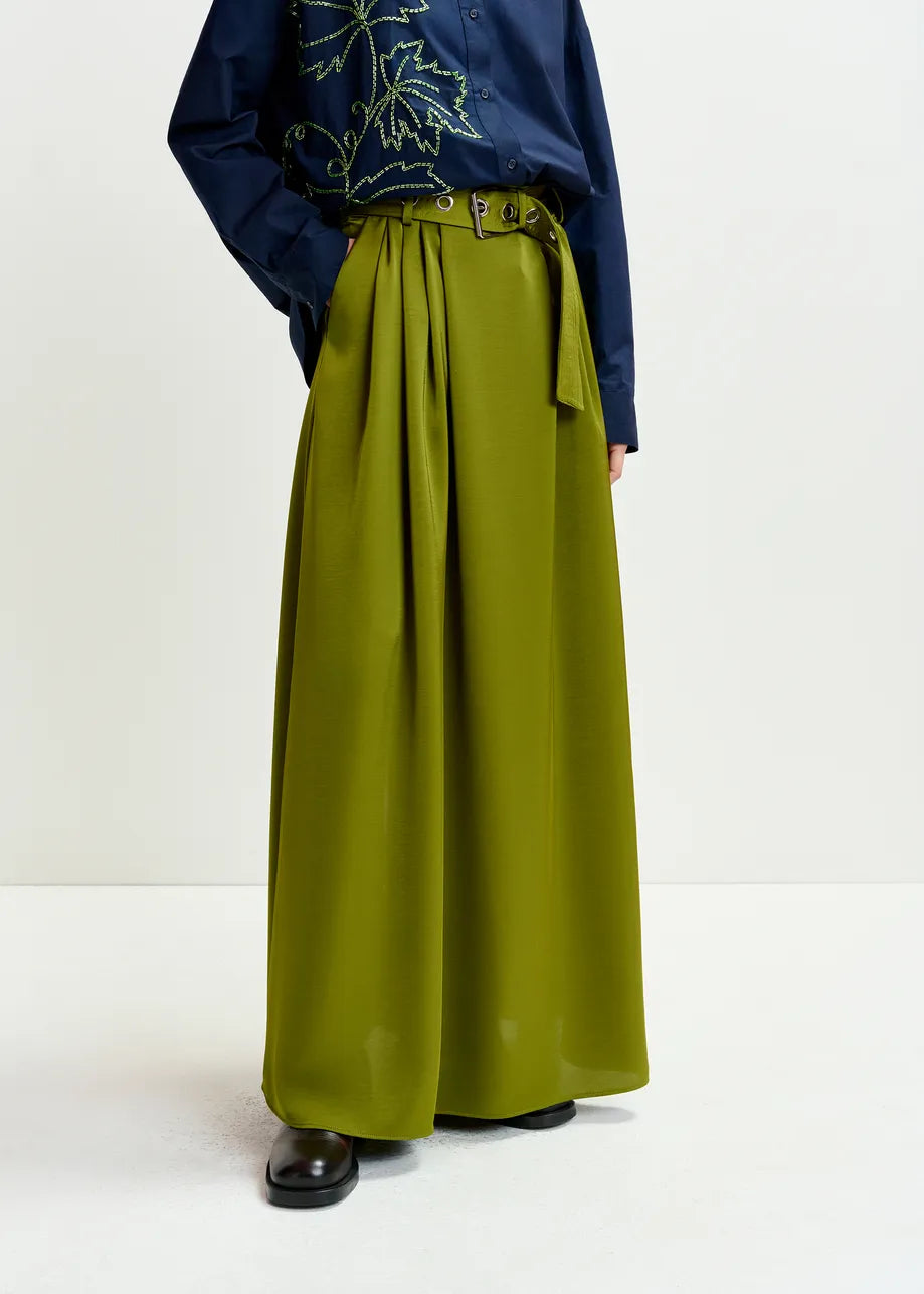 Person wearing a navy blue top with floral embroidery and a green wide-leg pants on a white background