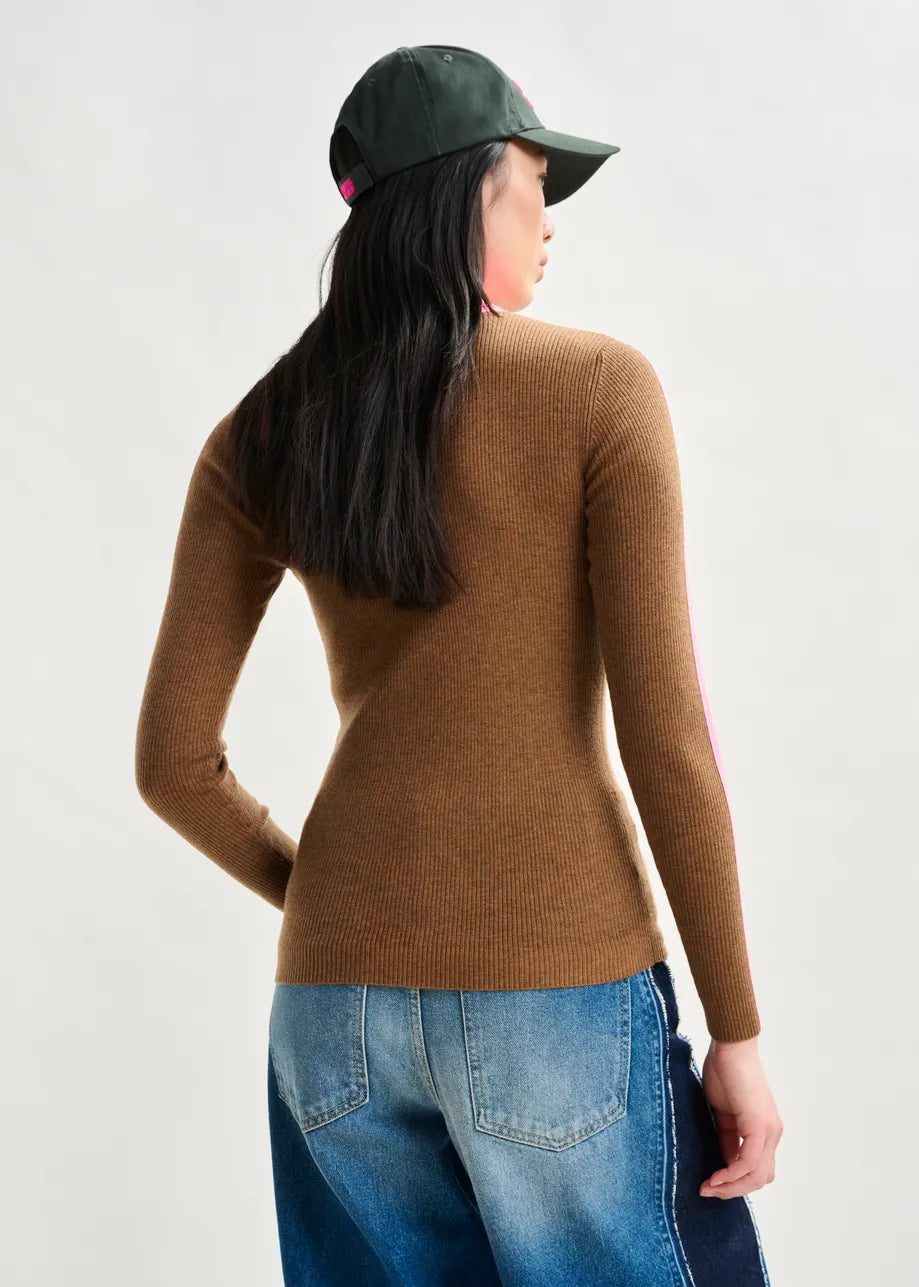 Person wearing a brown sweater and blue jeans with a green cap on a white background