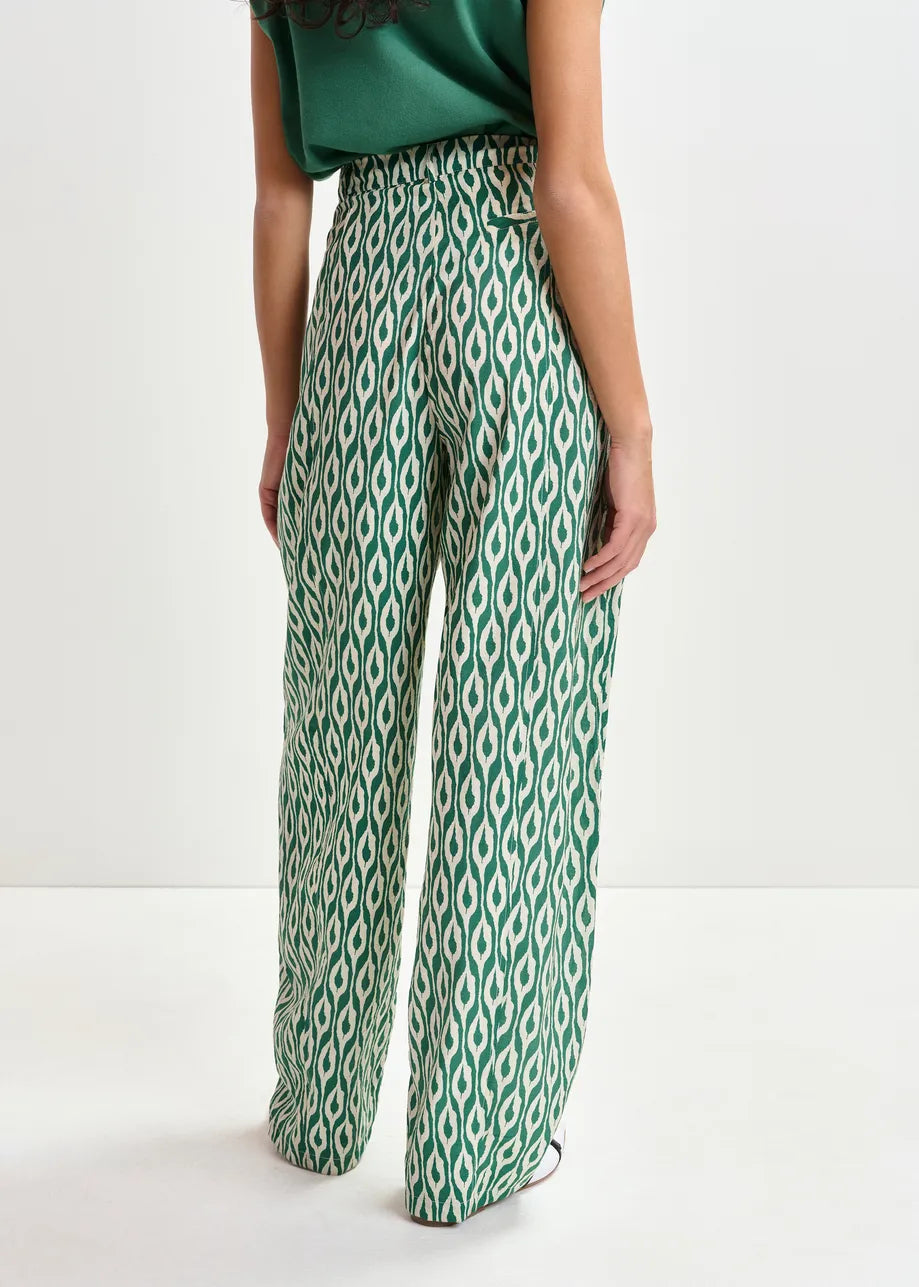 Green and white patterned pants worn by a person on a white background