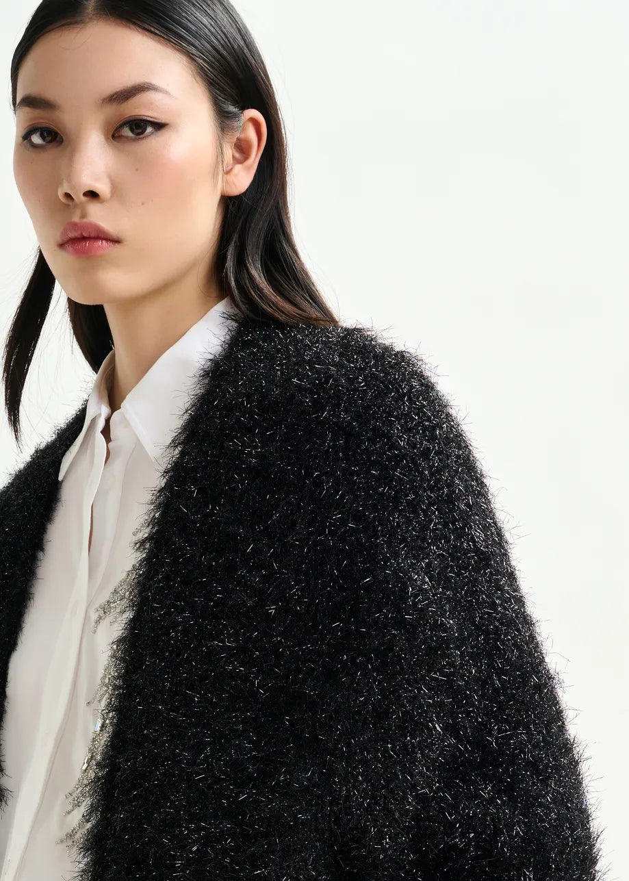 Woman wearing a black textured coat over a white shirt on a white background