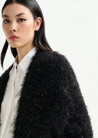 Woman wearing a black textured coat over a white shirt on a white background