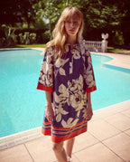 Woman in a floral SARA ROKA dress standing by a pool with greenery in the background shop online. front of dress.