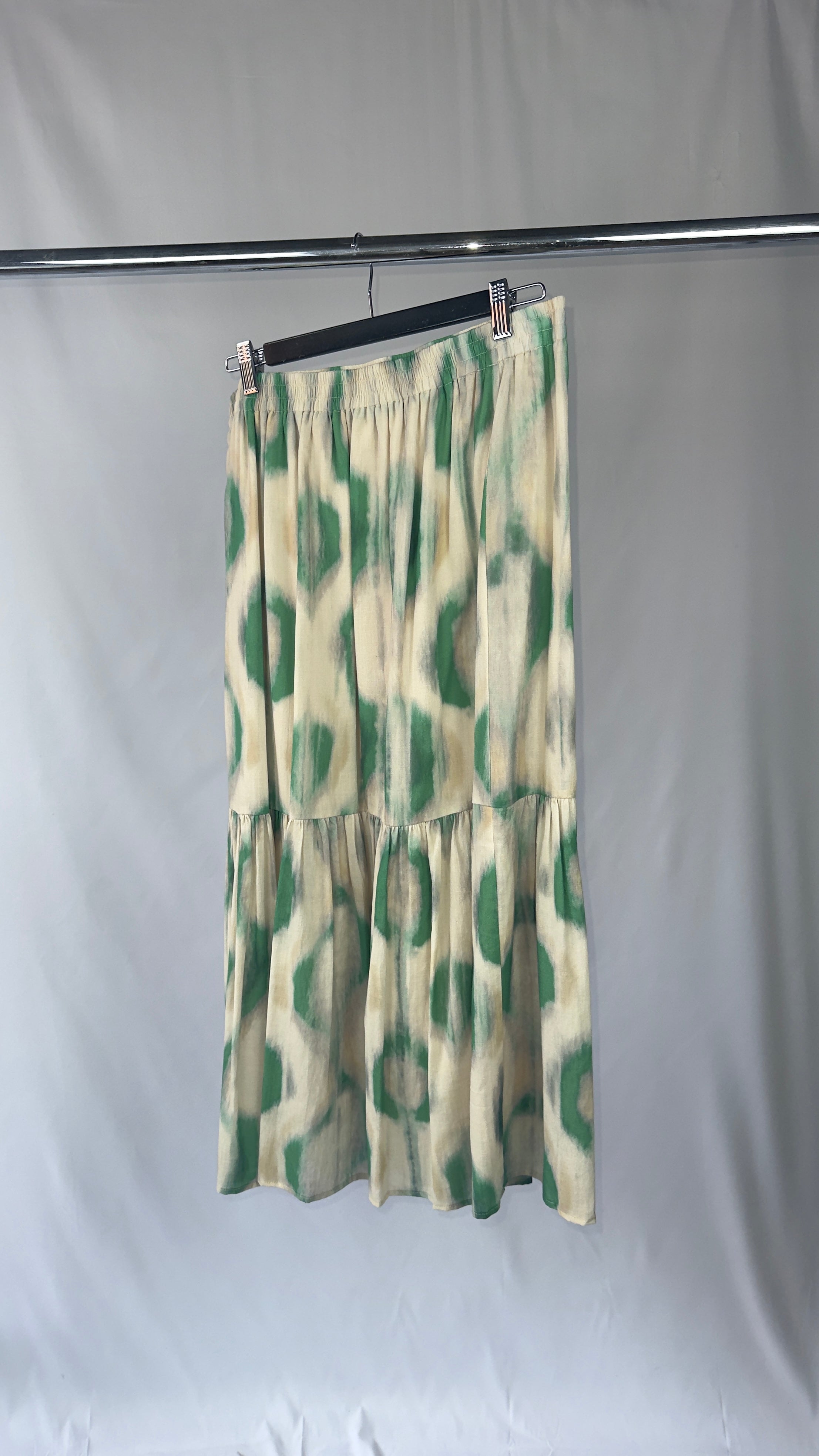Green and white patterned skirt on a rack against a plain background