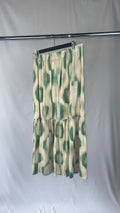 Green and white patterned skirt on a rack against a plain background