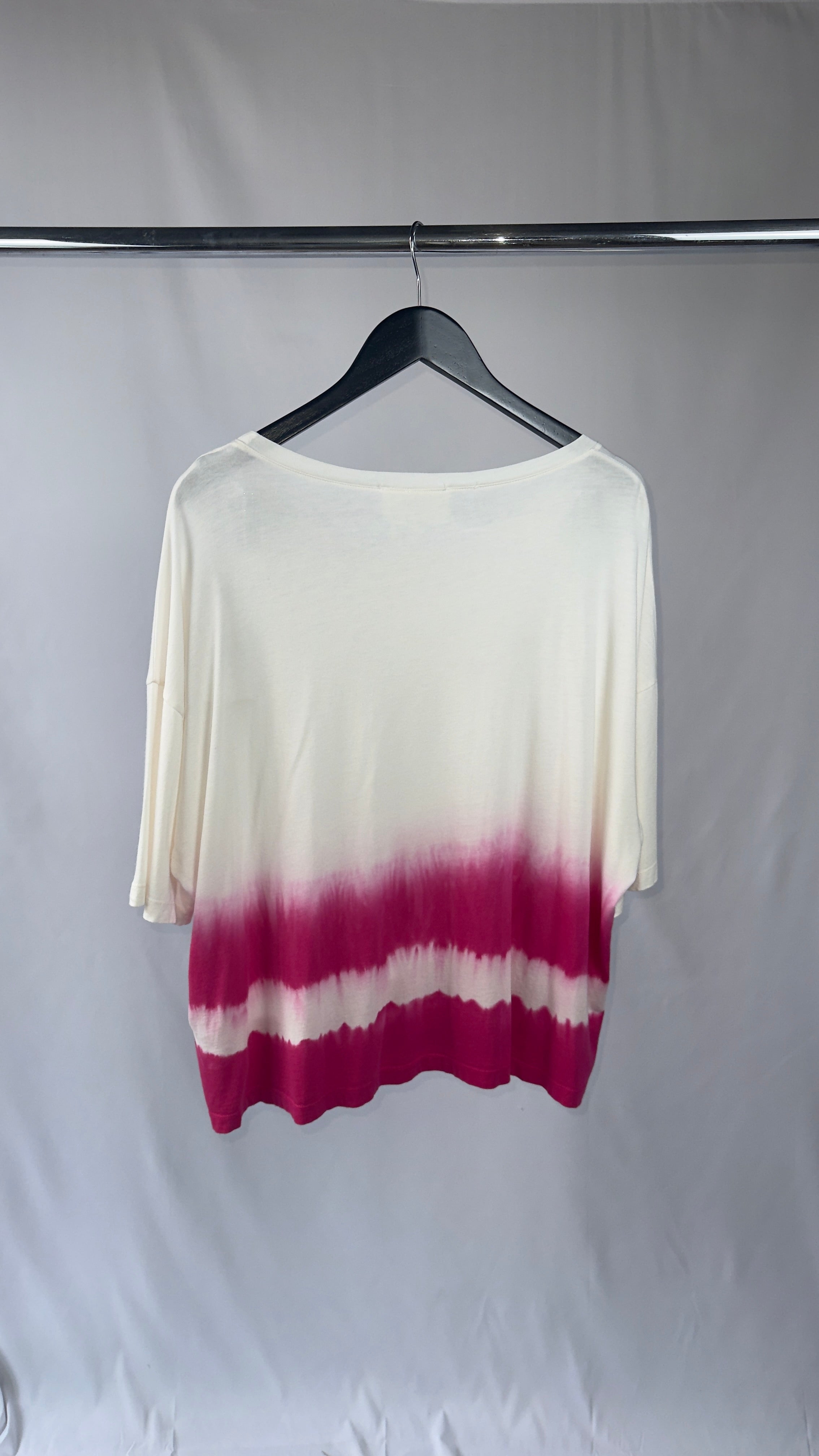 White and pink gradient top on a hanger against a plain background