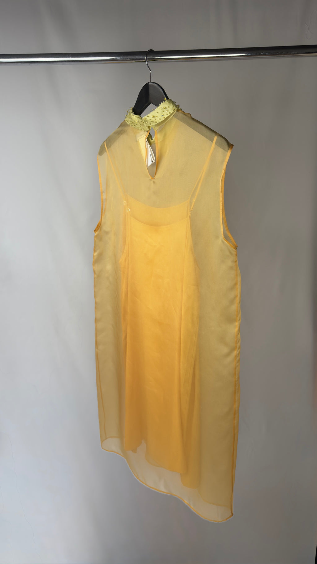 Yellow dress on a hanger against a white background
