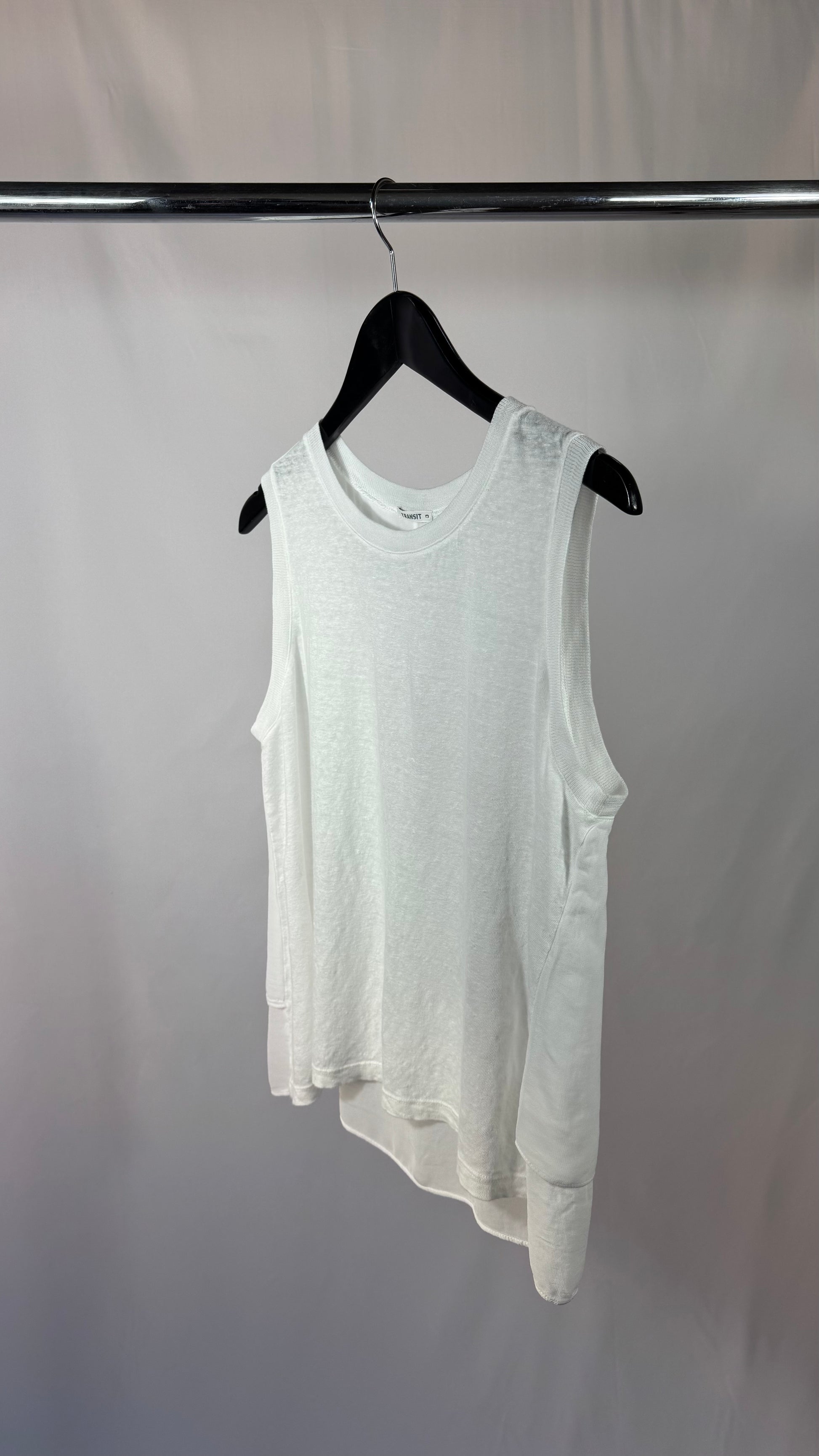 White sleeveless shirt on a black hanger against a plain background