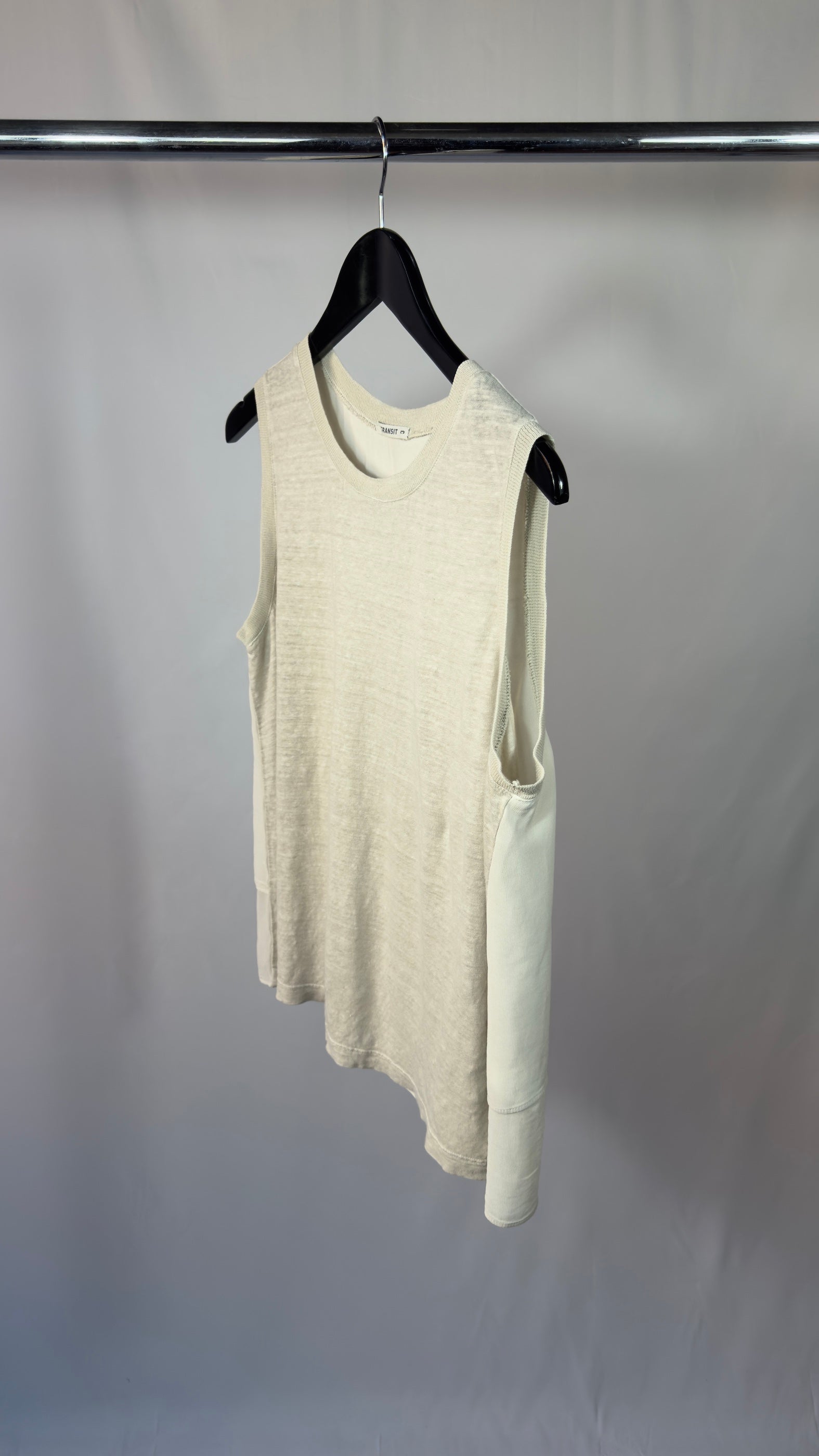 Beige sleeveless dress hanging on a black hanger against a plain background