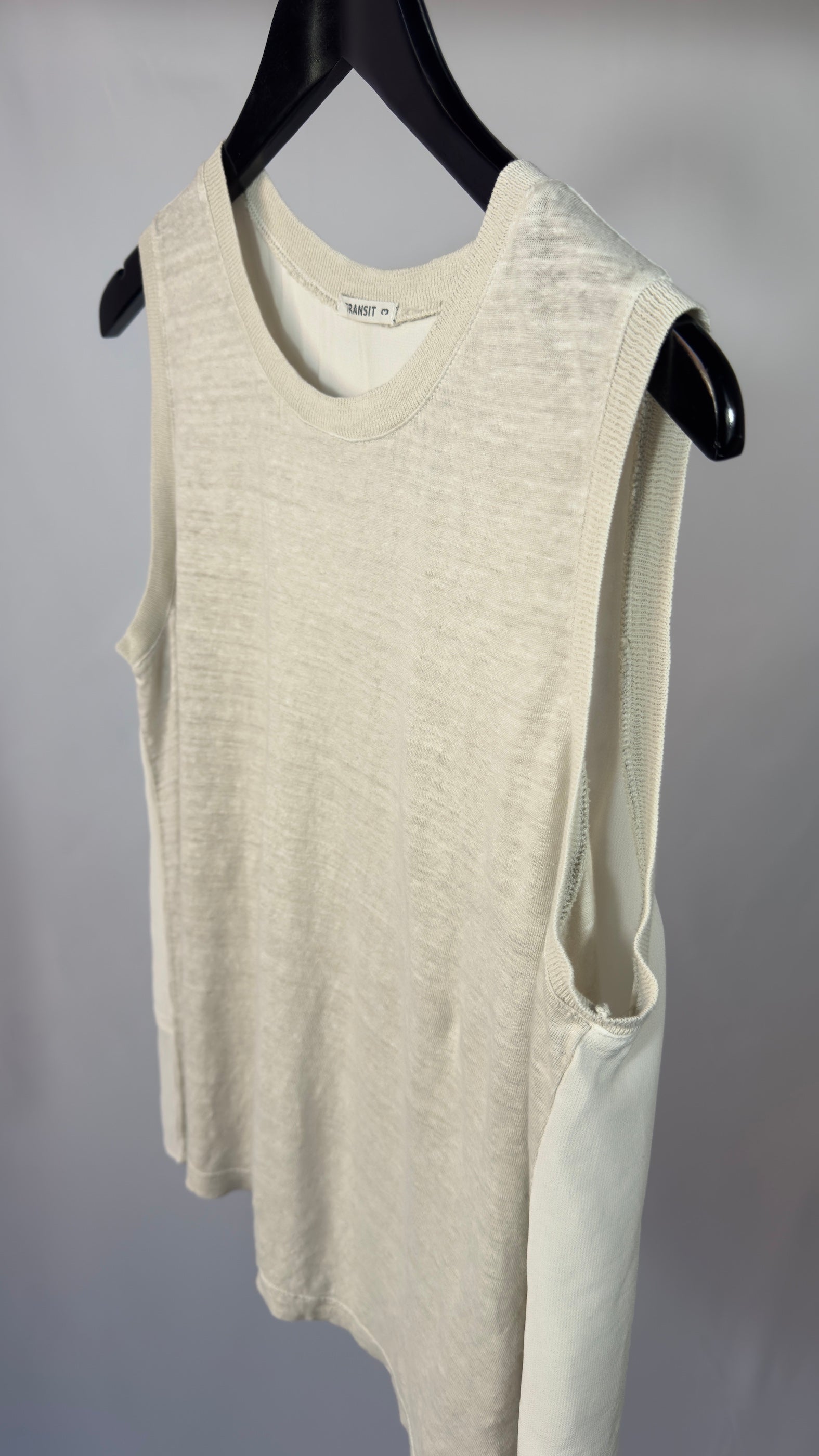Beige sleeveless top on a black hanger against a gray background