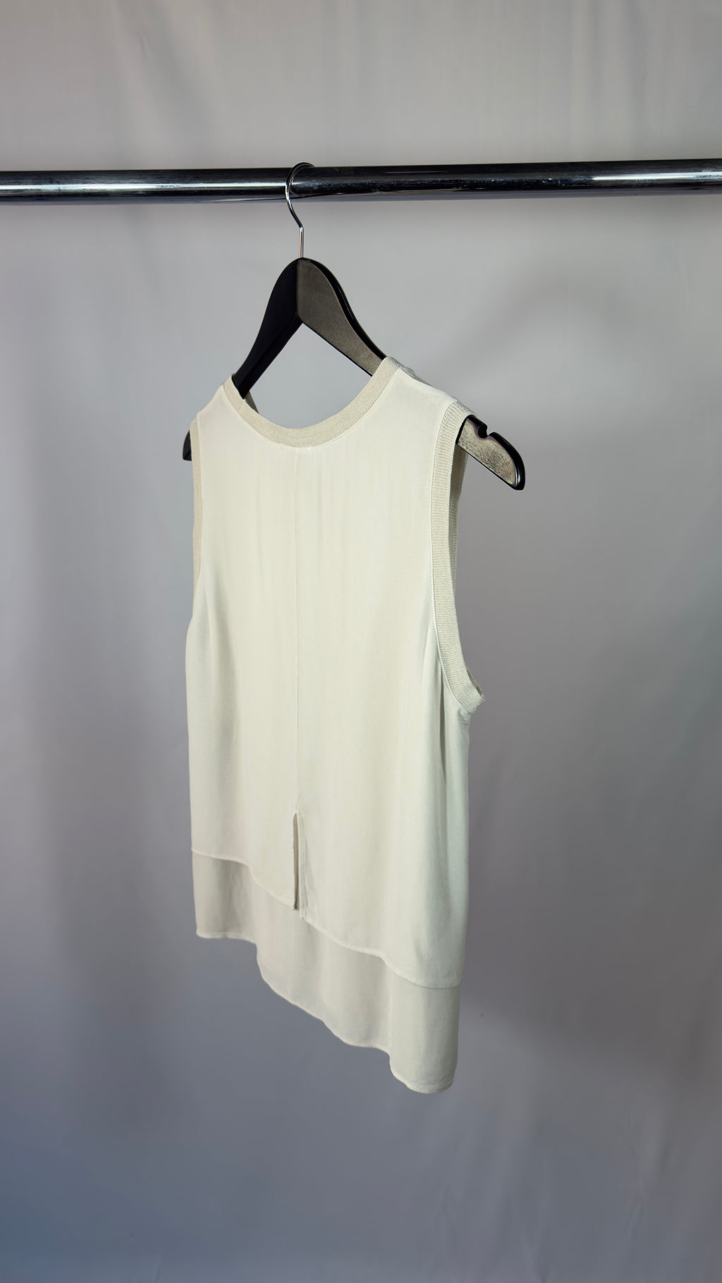 White sleeveless top on a hanger against a plain background