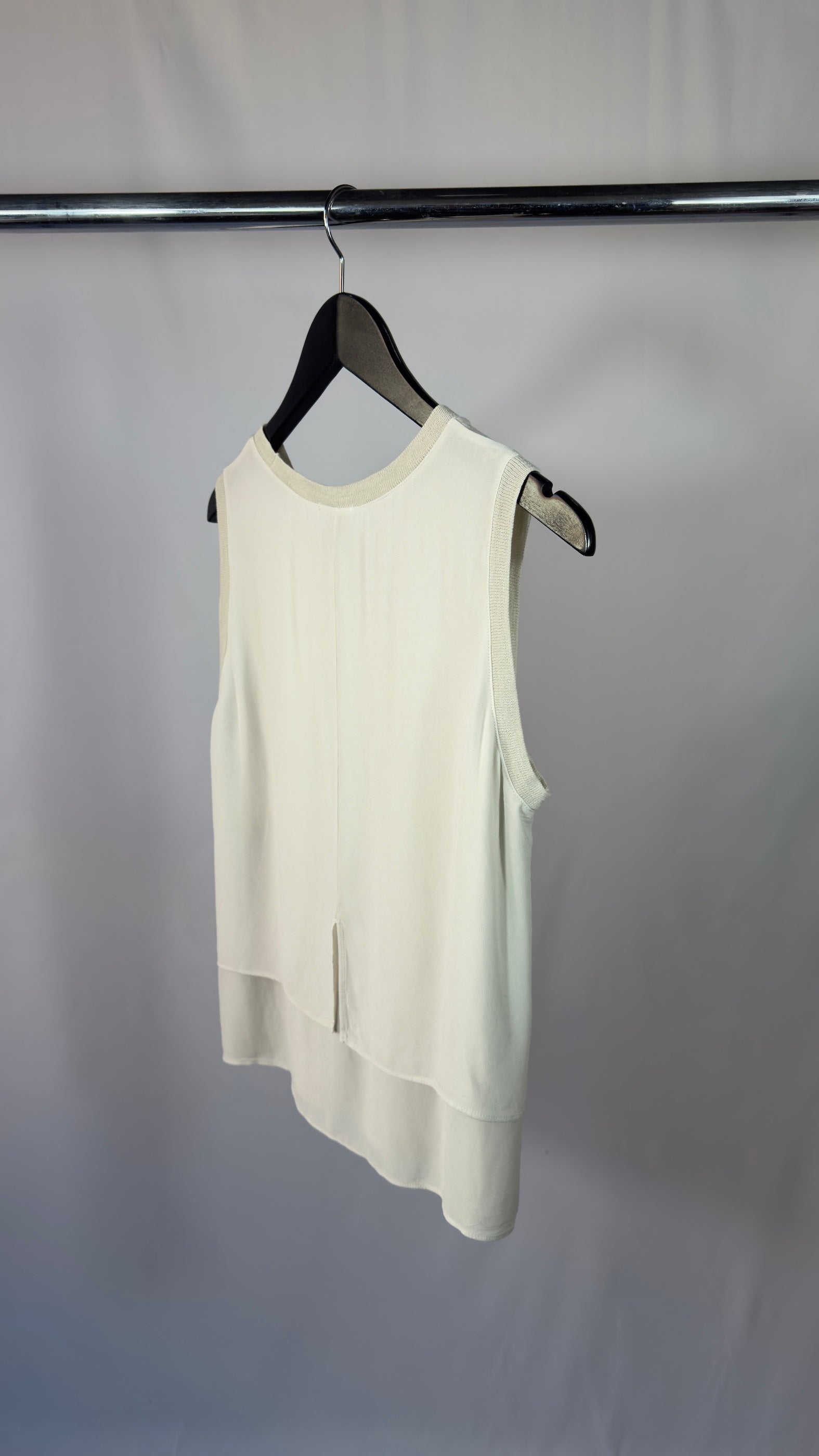 White sleeveless top on a hanger against a plain background