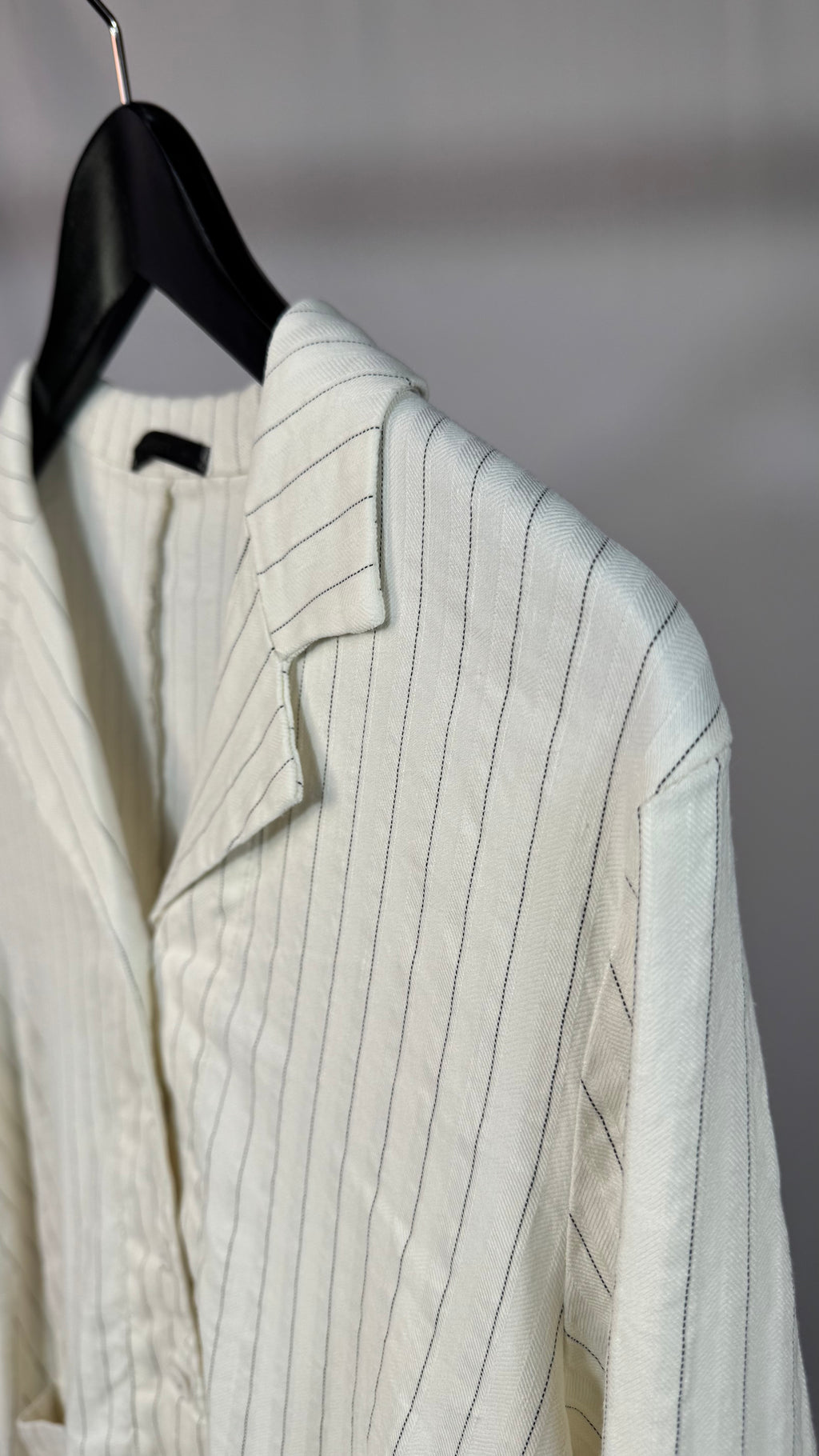 Light-colored pinstripe jacket on a hanger against a neutral background