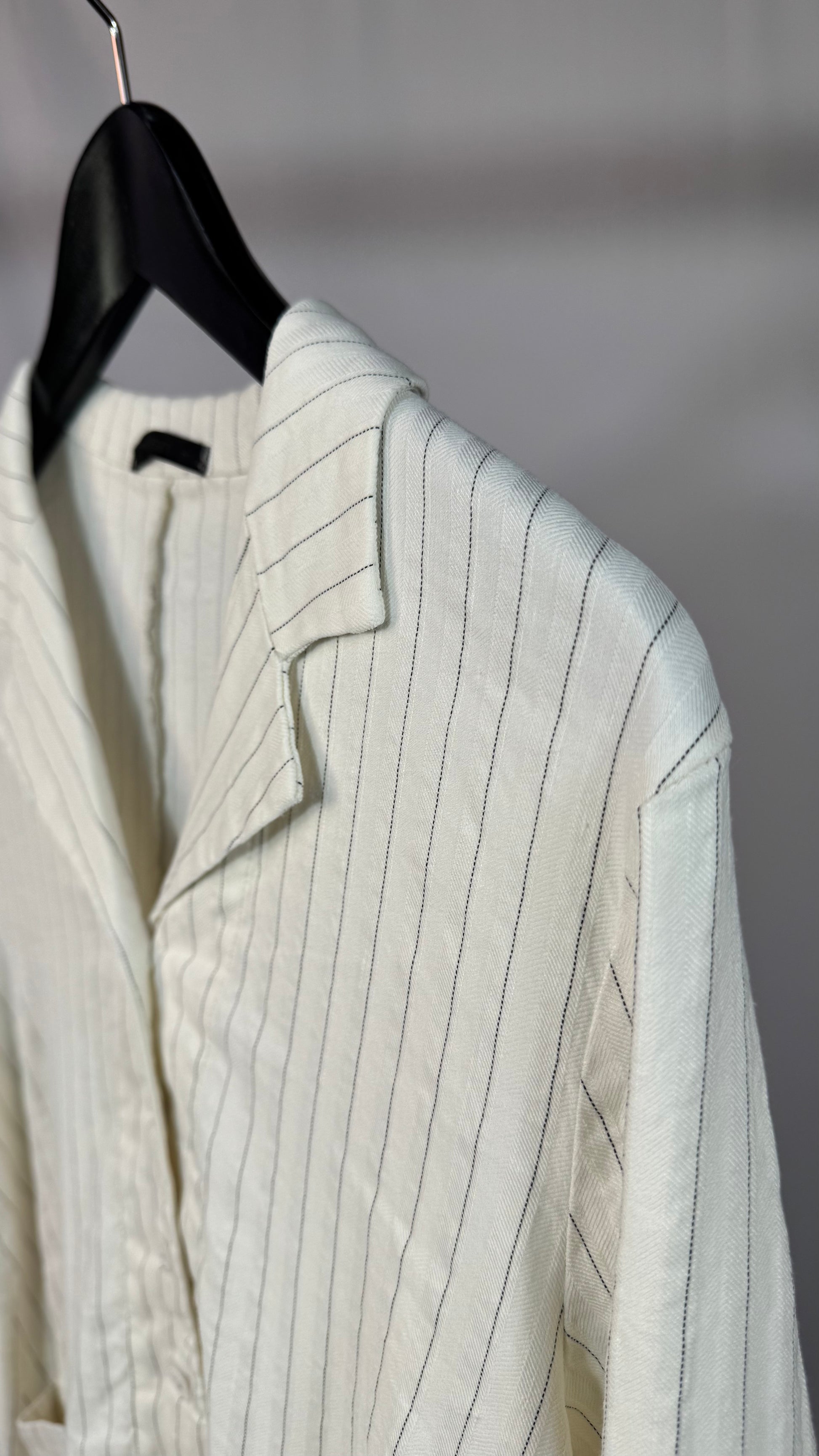 Light-colored pinstripe jacket on a hanger against a neutral background