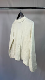White ribbed sweater on a hanger against a plain background