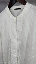 Light gray button-up shirt on a hanger with a neutral background
