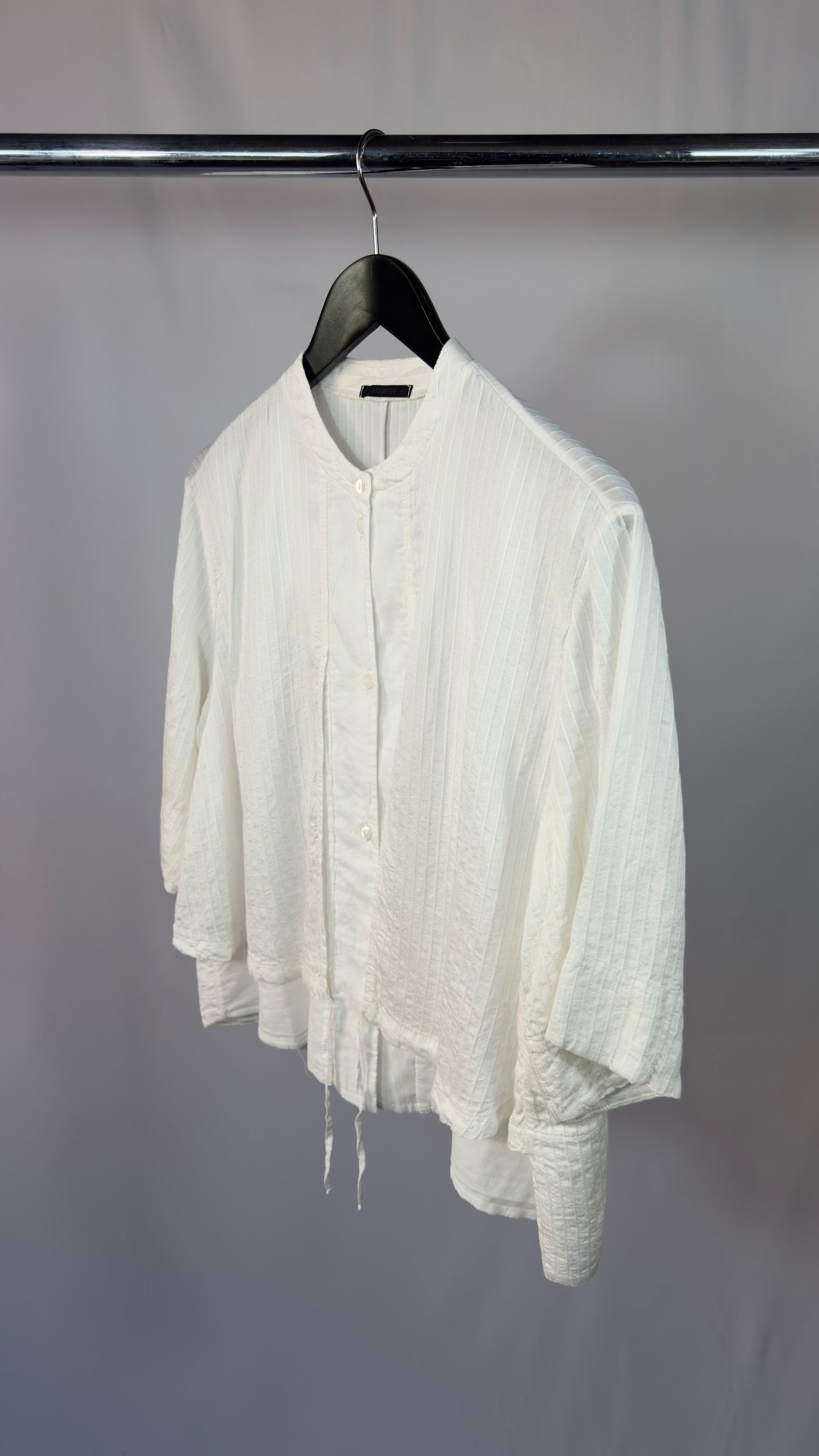 White shirt on a hanger against a plain background