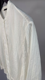 White textured shirt on a hanger against a neutral background