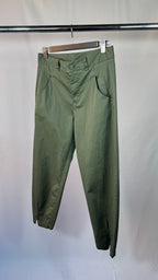 Green pants hanging on a rack against a white background
