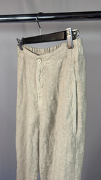 Beige pants hanging on a rack against a gray background