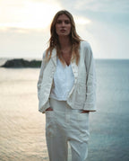 Woman in light clothing standing on a beach with ocean and sky in the background