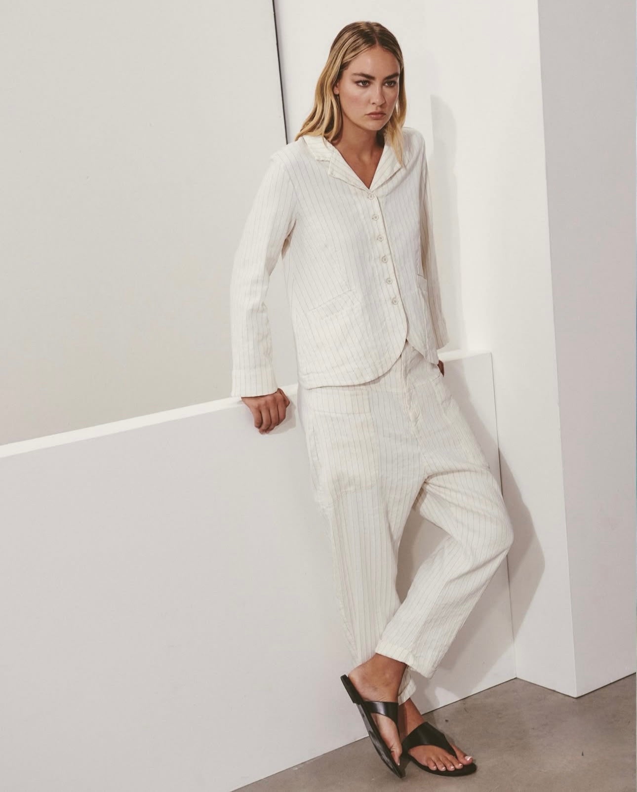 Woman in a white outfit standing against a plain background