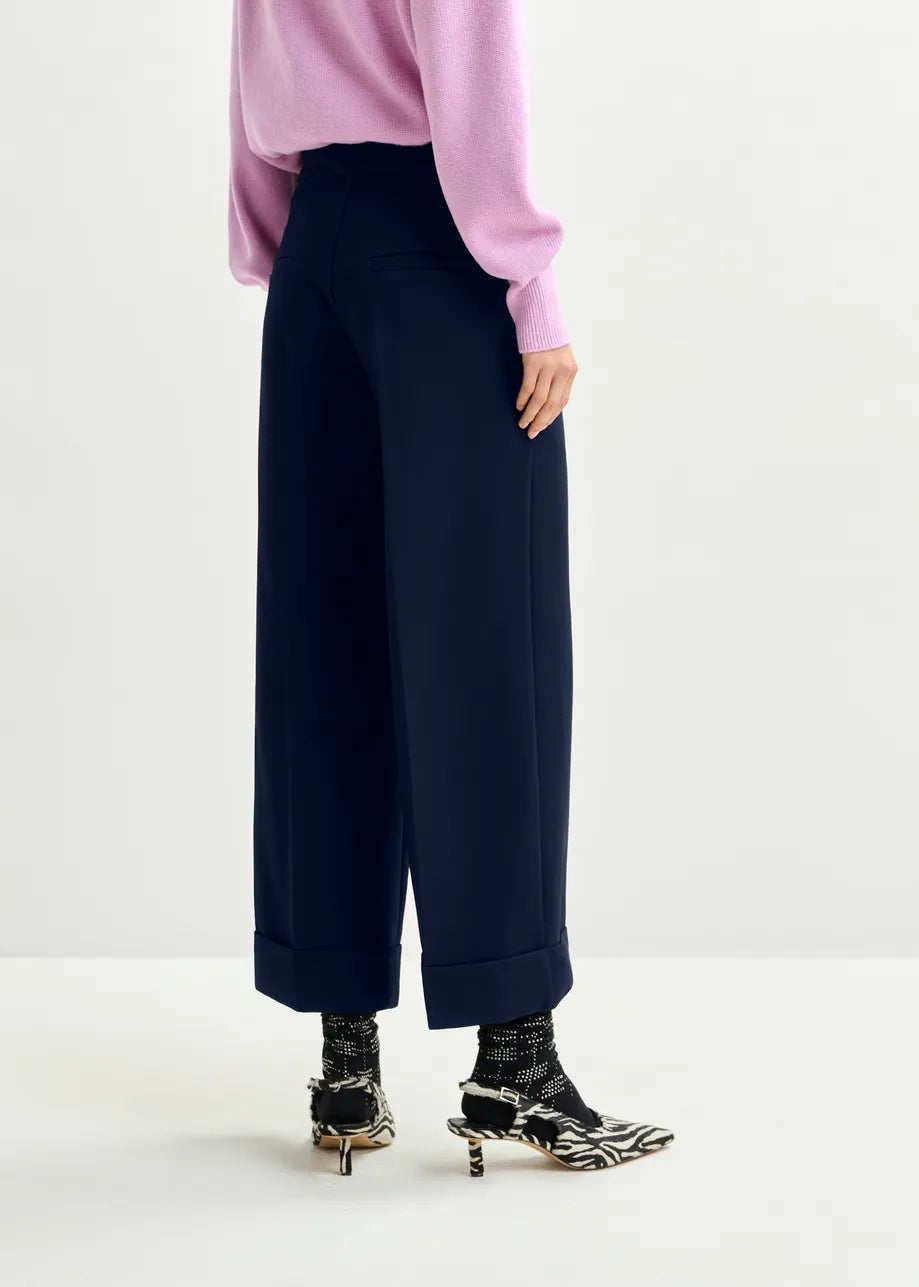 Person wearing navy wide-leg pants with a pink top on a white background