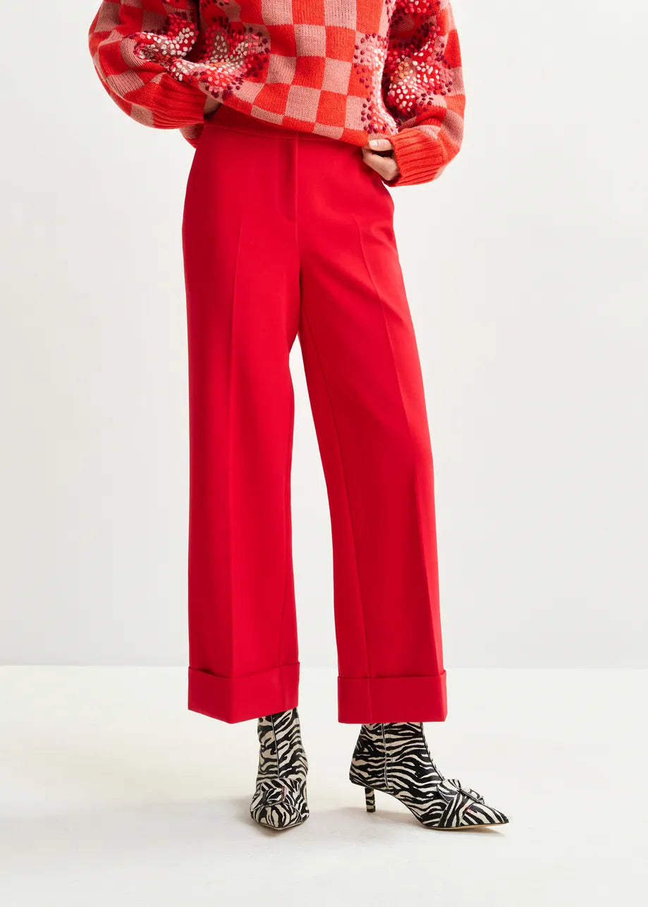 Person wearing a red outfit with a checkered sweater and red pants on a white background