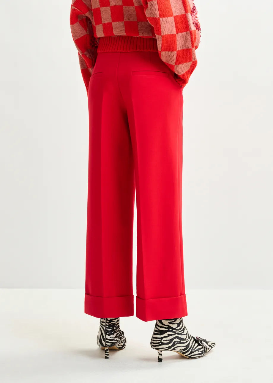 Person wearing red checkered sweater and red pants with zebra-striped shoes on a white background