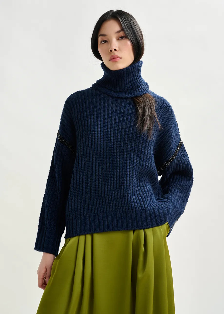 Woman wearing a blue sweater and green skirt on a white background