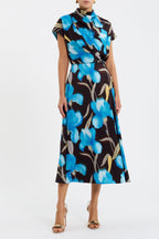 A midi-length floral print dress with a high cowl neckline, grown-on sleeves, and an A-line silhouette. The dress features a blue and black color scheme with a floral pattern.