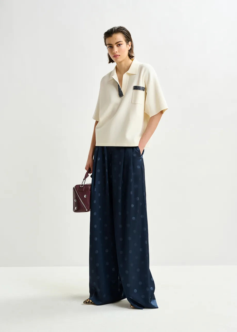 Woman wearing a white top and navy pants with a polka dot pattern on a white background