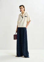 Woman wearing a white top and navy pants with a polka dot pattern on a white background