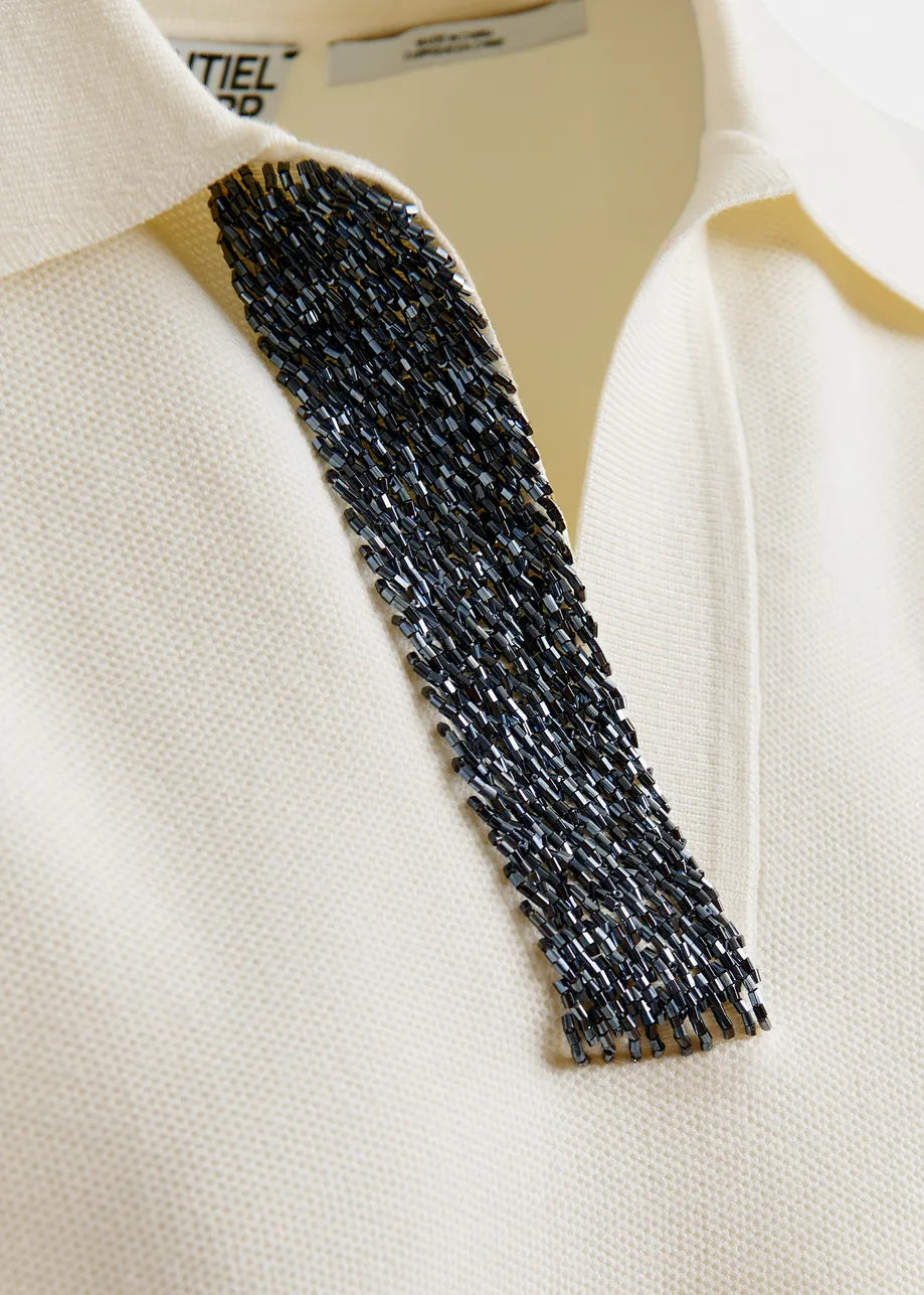 Close-up of a white garment with a textured black collar on a beige background