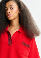 Woman wearing a red shirt with embellished collar and pocket on a white background