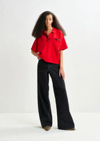 Woman wearing a red shirt and black pants on a white background